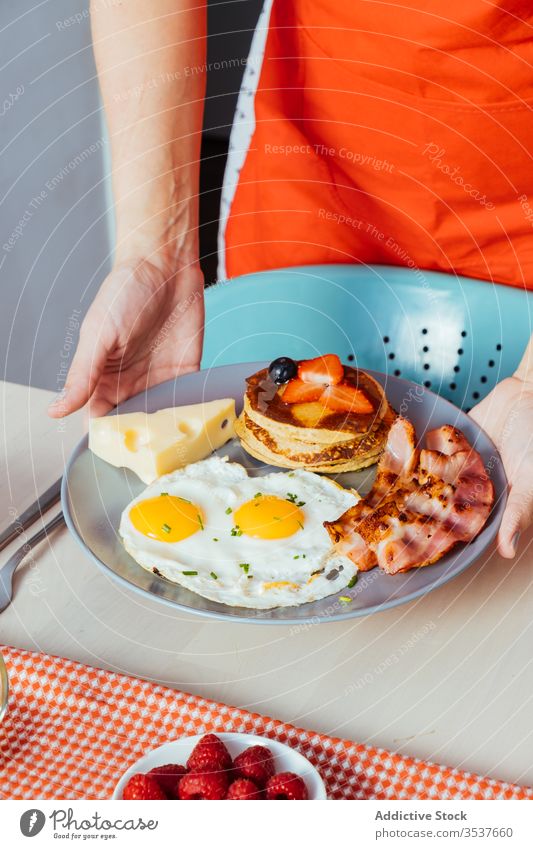 Anonyme Erntehelfer stellen zum Frühstück Teller mit Himbeeren und Honig auf den Tisch Liebling geschmackvoll Lebensmittel Hand Morgen süß frisch Gesundheit