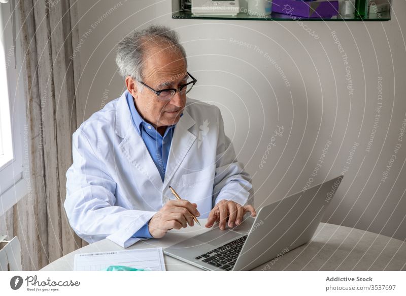 Älterer männlicher Arzt führt telemedizinische Beratung per Laptop in der Klinik durch arzt Telemedizin konsultieren Mann älter Gesundheitstelematik Ausbruch