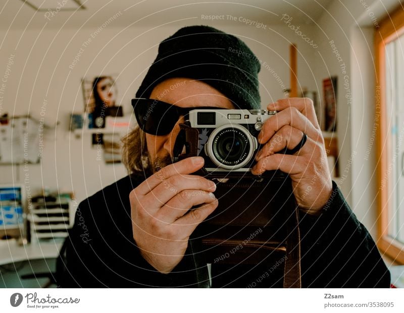 Der Fotograf kamera cool mütze sonnenbrille Selbstporträt selfi zuhause Wohnung Prüfung Mann junger Mann Hüfte Farbfoto Mode trendy Coolness Porträt