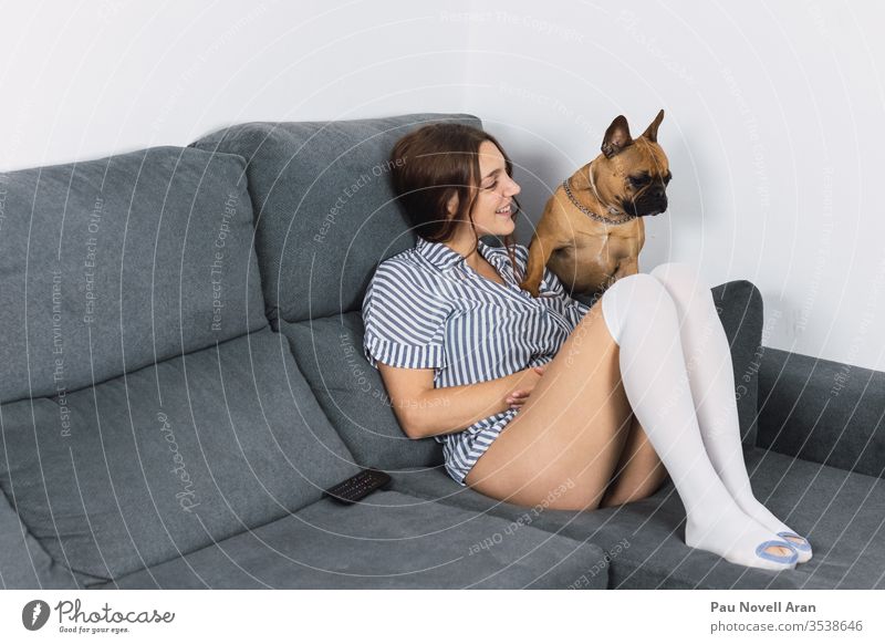 Sinnliche Frau mit französischer Bulldogge auf Sofa sitzend Hund im Innenbereich französische Bulldogge Lifestyle Haus Glück 20s lässig Kaukasier Tag LAZY
