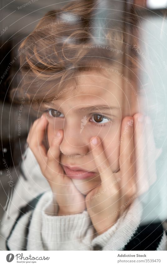 Gelangweilter Junge schaut aus nassem Fenster gelangweilt Regen Hand auf die Wange ruhen heimwärts gemütlich Wetter Kind traurig Kindheit ruhig Lifestyle einsam