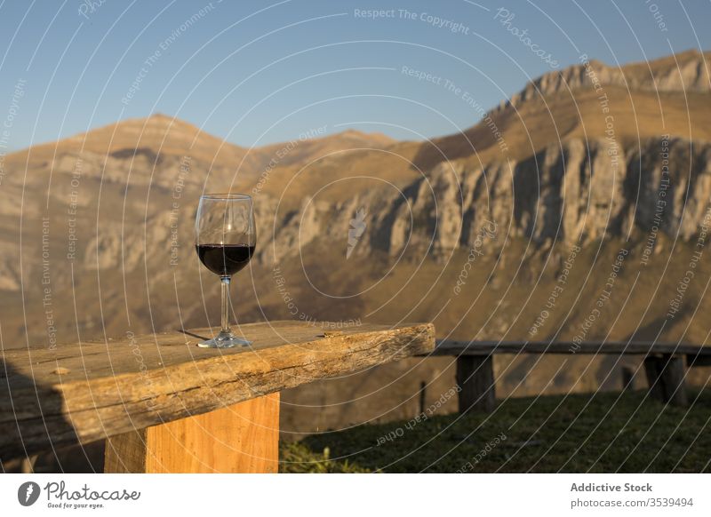 Glas Rotwein auf Holzgeländer gegen die Berge der Landschaft Wein Natur Berge u. Gebirge Wiese Sonnenuntergang Ansicht idyllisch rot hölzern Getränk Alkohol