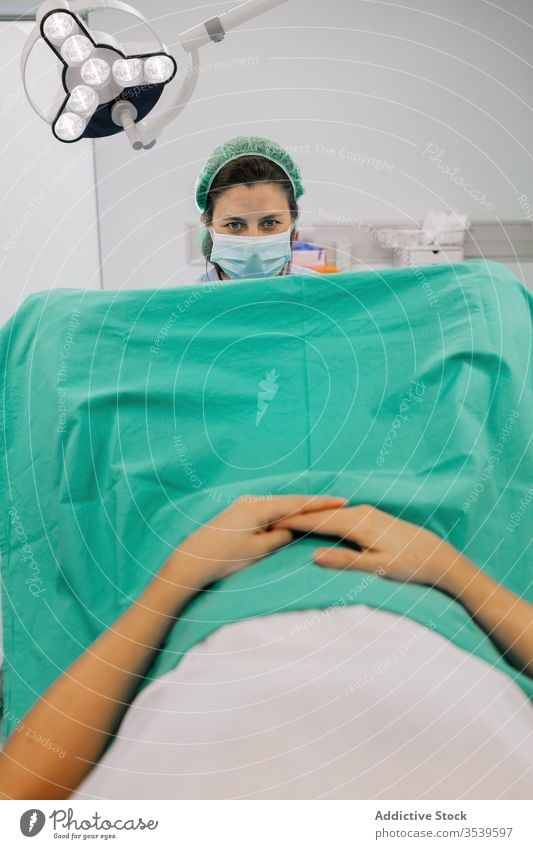 Gynäkologe untersucht anonyme Patientin in der Klinik Frauenarzt geduldig untersuchen gynäkologisch Stuhl steril Mundschutz medizinisch Gerät Fruchtbarkeit Arzt