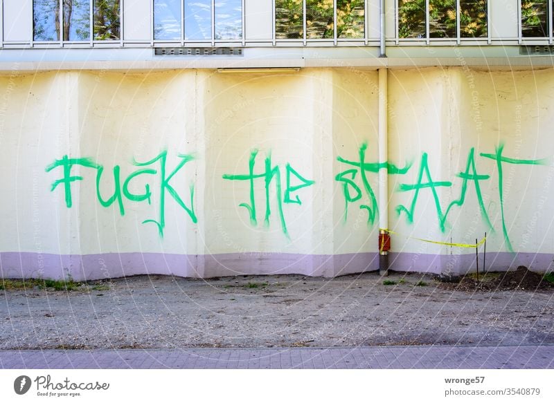 Fuck the Staat | Graffito an einer beigen Fassade Graffiti grün Schriftzug Schriftzeichen Mauer Wand Farbfoto Außenaufnahme Menschenleer Gebäude