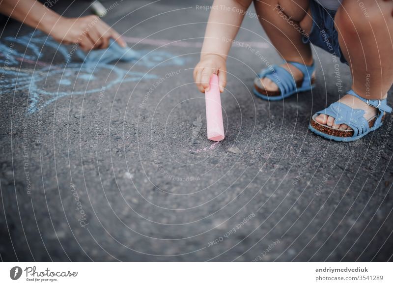 Nahaufnahme einer Zeichnung eines kleinen Mädchens mit Kreiden auf dem Bürgersteig Farbe Hand Straßenbelag wenig Kunst Sommer Hintergrund farbenfroh Spaß