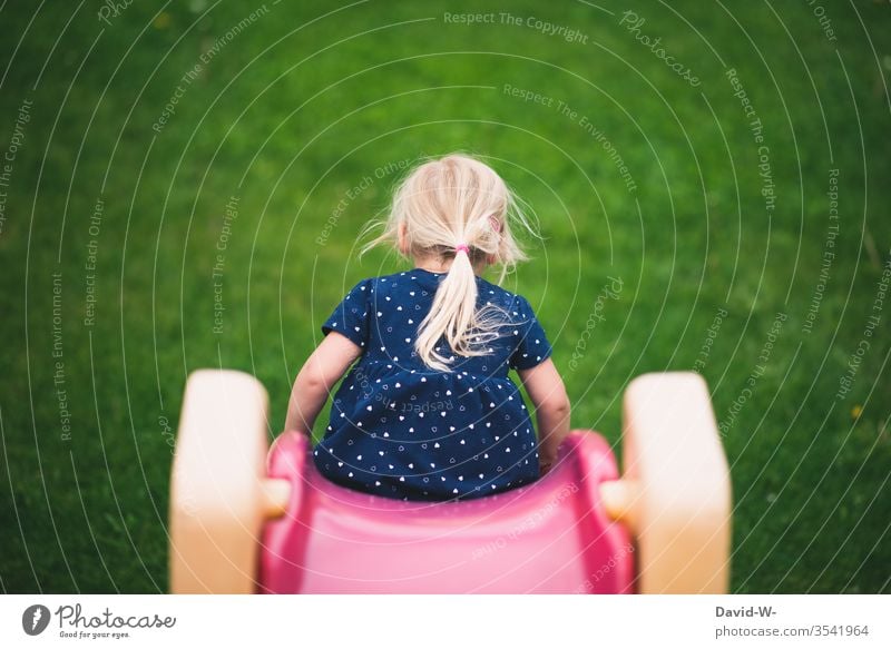 Kind rutsch die Rutsche hinunter Mädchen rutschen rutscht Garten Spielen draußen Natur Rückansicht Kindheit Freizeit & Hobby Freude Farbfoto Tag Kleinkind
