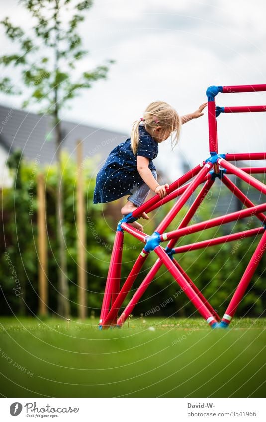Mädchen klettert auf einem Klettergerüst im Garten klettern Spaß freude mutig Kinder kindlich niedlich spielen beschäftigung Gartenspielzeug spielend greifen