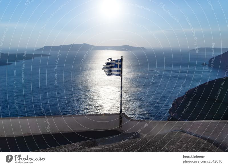 Zerrissene griechische Flagge im Gegenlicht des leuchtenden Ozeans der letzten Sonne, Santorin, Griechenland Fahne gerissen Sonnenuntergang gebrochen Insel MEER