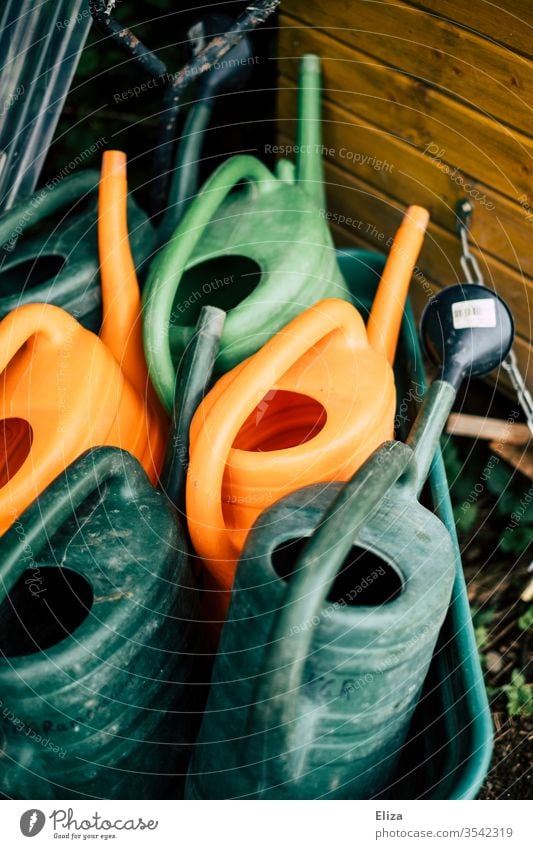 Verschiedenfarbige Gießkannen bunt grün orange Gartenarbeit Gärtner Wasser Geräte gießen leer Tag