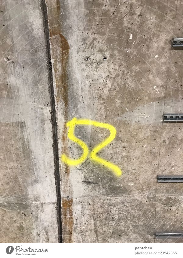 Gelbe Zahl 52 auf Betonmauer gesprüht. Markierung. Zahlen. zahlen gelb sprühen Graffiti markierung Wand Farbfoto Mauer Ziffern & Zahlen Zeichen