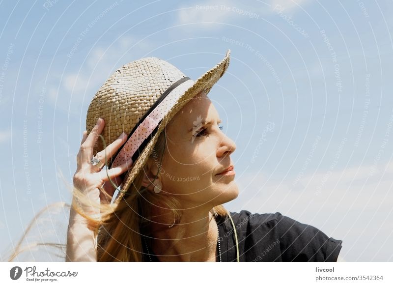 Frau mit Borsalino-Hut, die die Sommersonne an der Küste genießt Surfer genießend Menschen blond MEER Lifestyle Porträt Gesicht Stil Posen attraktiv Ufer