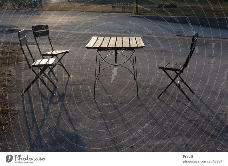 Tisch und Stühle in der Abendsonne Straße Asphalt Klappstuhl Klapptisch Möbel Gartenmöbel Straßencafé leer Sitzgelegenheit abends Licht leuchten Schatten