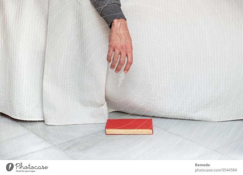 Person schläft beim Lesen eines Buches im Bett ein und lässt das Buch auf den Boden fallen. Begriff der Langeweile zu Hause. Bohrung schlafend lesen Melancholie