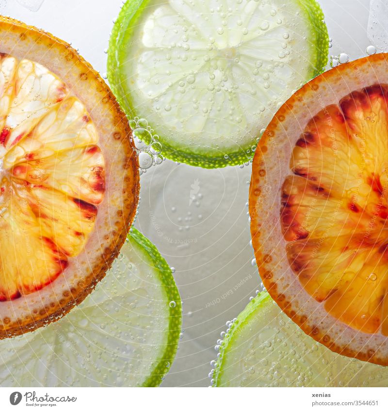 Orangen und Limetten schwimmen in Scheiben geschnitten auf Wasseroberfläche grün Luftblasen Frucht Diät Ernährung Gesundheit frisch rund Gesunde Ernährung