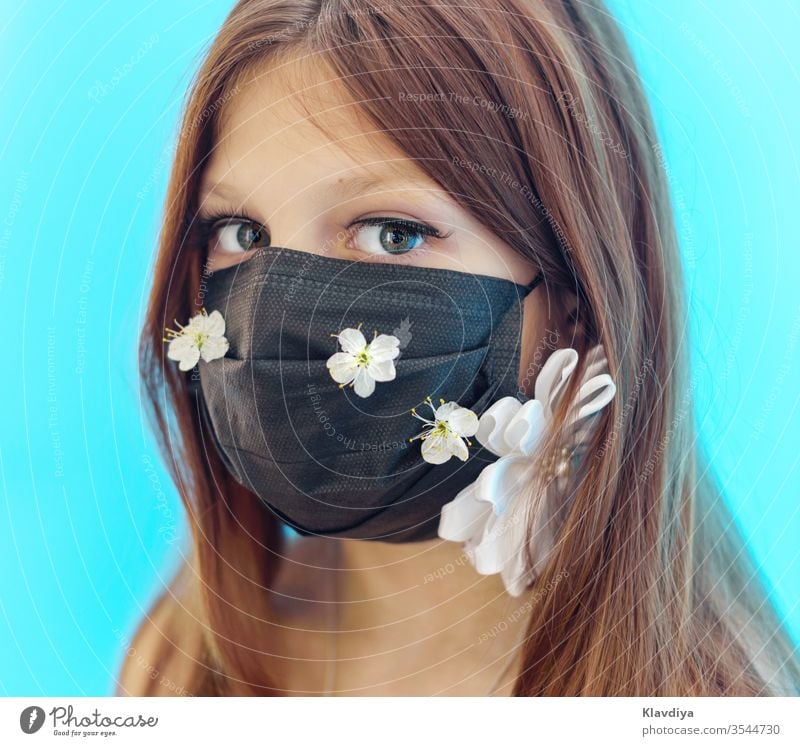 ein Mädchen mit einer schwarzen Gesichtsmaske, die mit Blumen auf blauem Hintergrund verziert ist Schönheit atmungsaktiv Pflege Kaukasier Kind