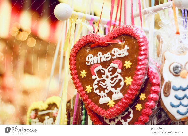 „Frohes Fest“ steht auf einem Lebkuchenherz. Weihnachten. Weihnachtsmarkt. Kitsch. Leuchten. lebkuchenherz weihnachtsmarkt stand kitsch süßigkeit tradition