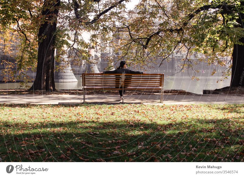 Frau mit Fluss vor sich, während sie auf einer Parkbank sitzt Album Appartement Rücken Kontemplation Gardine Fundstück Tür elegant Genuss ethnisch Erkundung