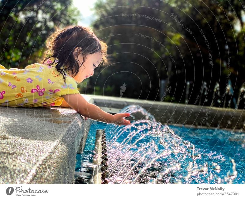 Mädchen spielt mit Wasserfontäne bei Sonnenschein Lifestyle Erfrischung Geplätscher Sonnenlicht Kleinkind wenig Person Licht Lachen erwärmen Sprinkleranlage