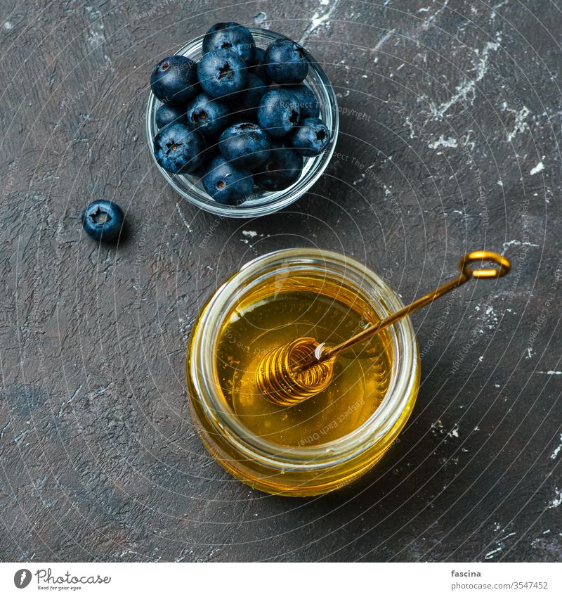 Heidelbeeren und Honig auf dunklem Hintergrund, Draufsicht Blaubeeren Liebling Gesundheit Lebensmittel Zutaten Glas Abblendschalter frisch klein
