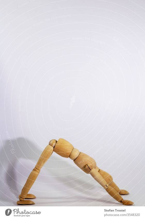 Holzpuppe während der Yogapraxis Ansanas, nach unten schauender Hund, vor weißem Hintergrund Puppe Körper Dummy Gleichgewicht Figur Fitness gestikulieren Probe