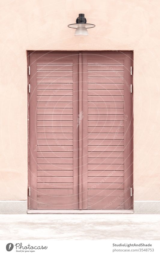 Rosa Gebäude mit einer Holztür Tür Eingang rosa rot Pastell zugeklappt hölzern Haus heimwärts Lampe Straßenlaterne Außenseite Großstadt Stadt urban Europa