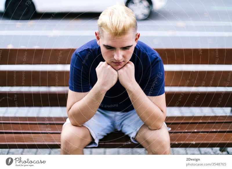 Junger Junge sitzt auf einer Bank auf der Straße, die Hände im Gesicht, besorgt und traurig Mann 1 männlich Hand Person jung Single Sorge Stress Park