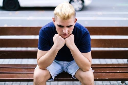 Junger Junge sitzt auf einer Bank auf der Straße, die Hände im Gesicht, besorgt und traurig Mann 1 männlich Hand Person jung Single Sorge Stress Park