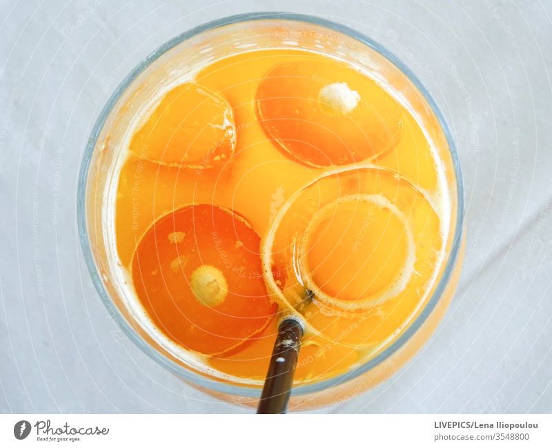 ein Orangensaft in einem Glas, sieht aus wie ein Gesicht orange Textfreiraum Auge Eis Eiswürfel Saft heller Hintergrund Mund Orangen-Scheiben Natur Frische