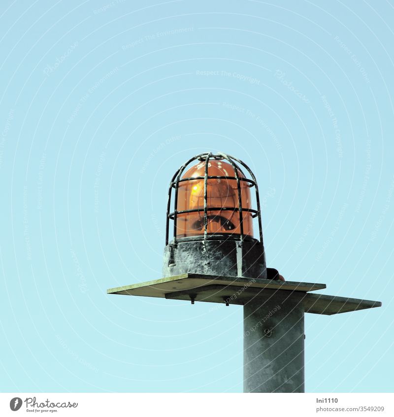 Warnleuchte auf Konsole eines Laternenpfahls geschraubt Warnung Gefahr Mast Vogelkot orange hoch Stange Achtung blauer Himmel Helgoland Düne Flugplatz Metall