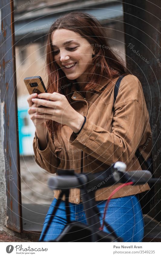 Junge Frau betrachtet Smartphone auf der Straße Stadtleben Lifestyle urban schön Mitteilung Anschluss Gerät Europa Außenseite Apparatur Internet Model Holz