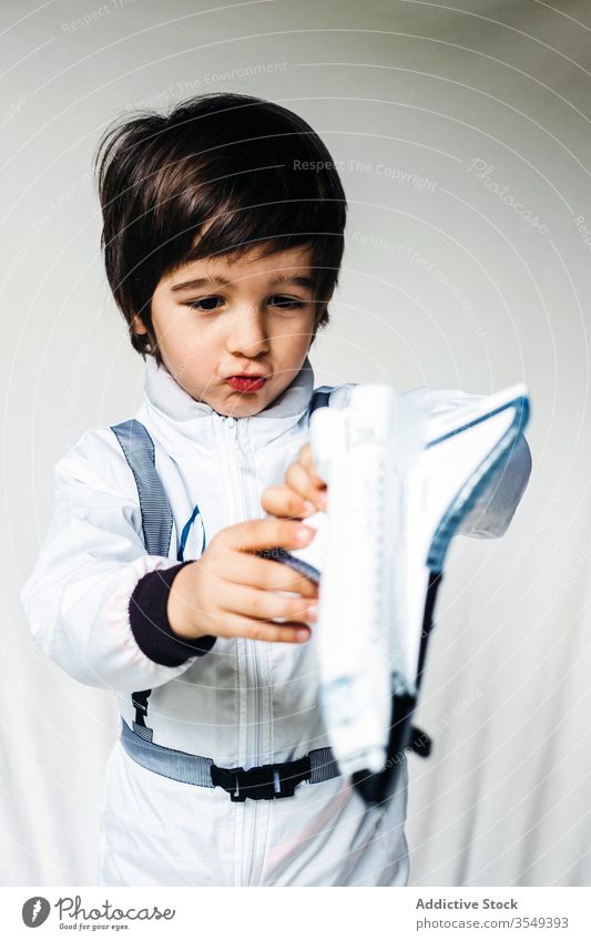 Anbetungswürdiger Junge im Kosmonautenkostüm auf weißem Hintergrund Tracht bezaubernd Raumfahrer Spielzeug Raumschiff Kind Astronaut Raumanzug Uniform