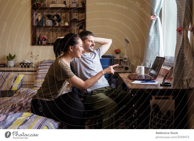 Multiethnisches verliebtes Paar schaut sich einen Film auf dem Laptop an zuschauen Schlafzimmer Zusammensein diskutieren Video benutzend rassenübergreifend
