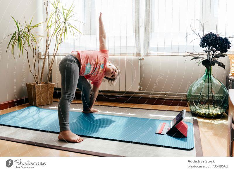Kleines Mädchen, das Yoga in erweiterter Seitenwinkelstellung praktiziert Kind Asana üben heimwärts erweiterte Seitenwinkelstellung Tablette