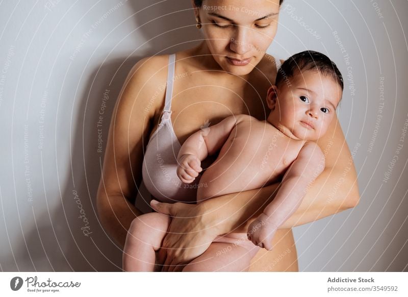 Mutter hält kleines Baby auf Händen im Zimmer Frau Liebe Kuss Dessous Umarmen Zusammensein Angebot sanft Unterwäsche Pflege Kind Mutterschaft jung Glück