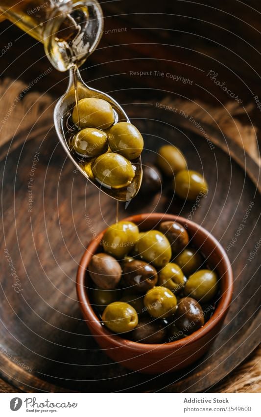 Erntehelfer gießt Öl auf Oliven oliv Erdöl eingießen Löffel Schalen & Schüsseln Tisch Person hölzern Küche extra jungfräulich Kannen Glas Flasche Karaffen