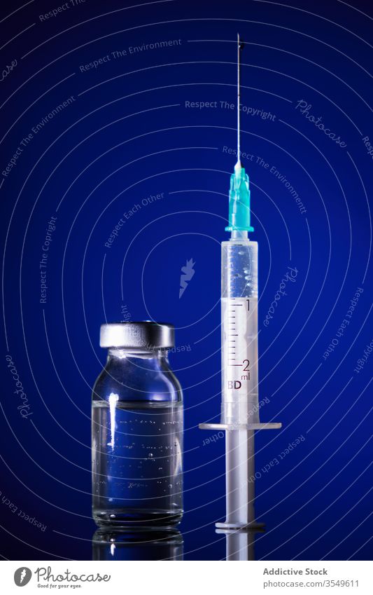 Kleine Medikamentenflasche und Spritze auf blauem Hintergrund Medizin Impfstoff Abhilfe Virus Infektion Kur heilen Bund 19 Coronavirus Leckerbissen Antibiotikum
