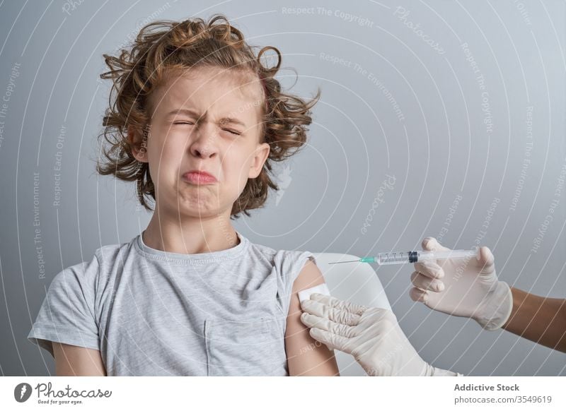 Anonymer Arzt hält Jungen während der Injektion in der Klinik an der Schulter Impfstoff Einspritzung Leckerbissen Spritze Medizin Handschuh geduldig