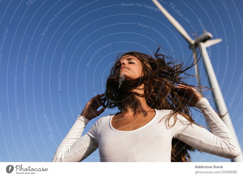 Zarte Frau tanzt allein in der Nähe des Windparks auf sonnigem Feld Tanzen Landschaft sinnlich Natur Ökologie schlank Stil alternativ Windmühle Energie