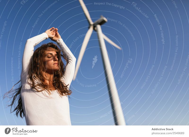 Zarte Frau tanzt allein in der Nähe des Windparks auf sonnigem Feld Tanzen Landschaft sinnlich Natur Ökologie schlank Stil hochreichen alternativ Windmühle