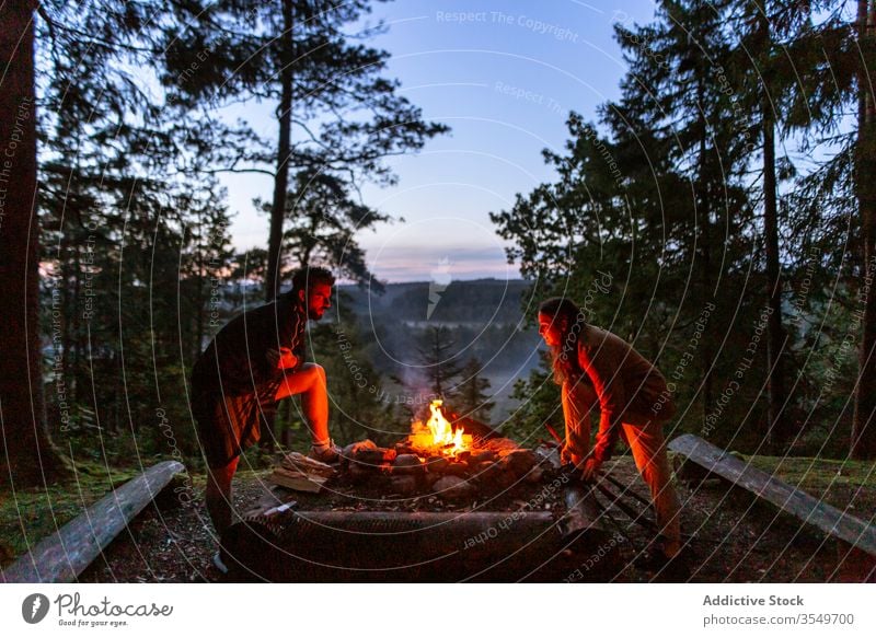 Paar mit Brennholz beim Lagerfeuermachen im Wald Wohnmobil Freudenfeuer Nacht Totholz Aufwärmen Freunde Reisender Wälder genießen Abend Frau Zusammensein Mann