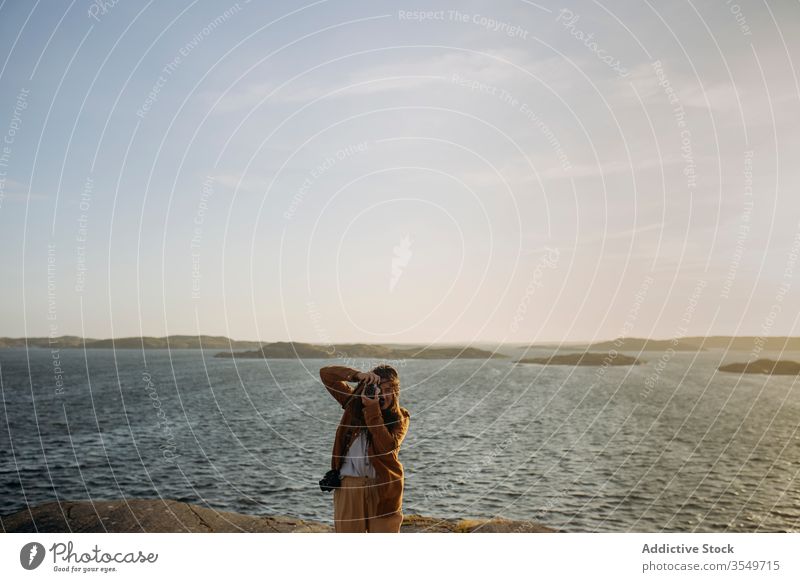 Anonyme Touristin, die am felsigen Meeresufer steht und Fotos macht Frau fotografieren Klippe Küstenlinie Meereslandschaft Natur MEER Reise Fotoapparat