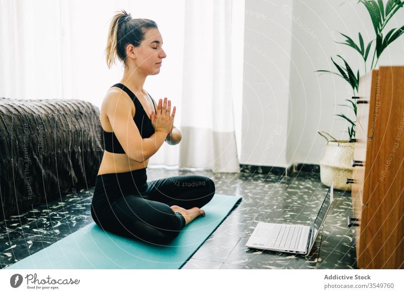 Junge Frau, die zu Hause online Yoga praktiziert meditieren Laptop heimwärts Lotus-Pose Namaste Windstille jung gestikulieren Tutorial üben Wellness Asana Gerät