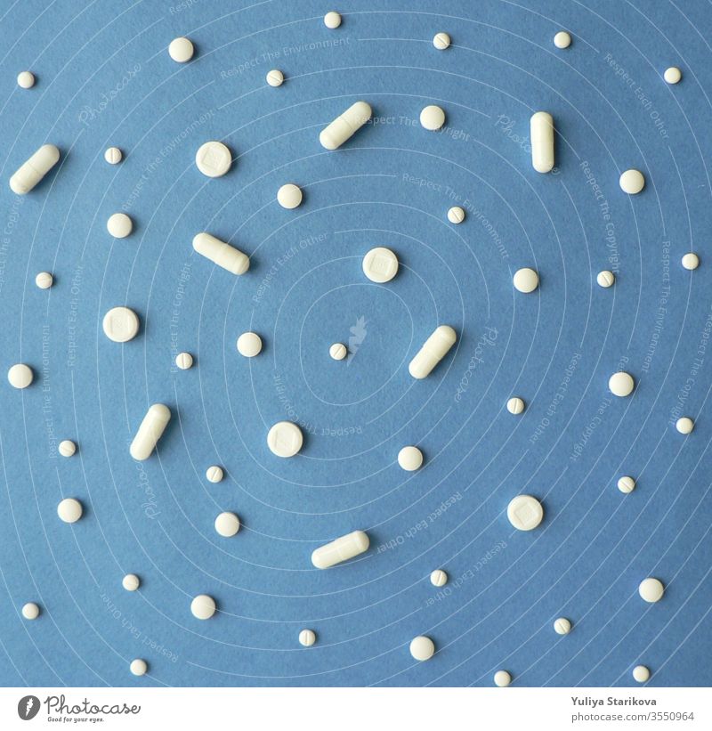 Kreative, skandinavisch anmutende, flachliegende Draufsicht von weißen Pillen und Kapseln auf blauem Hintergrund. Behandlung und der Hoffnung auf Genesung. Kreative Idee für Drogerie, Online-Apotheke, Health Lifestyle und Geschäftskonzept eines Pharmaunternehmens.