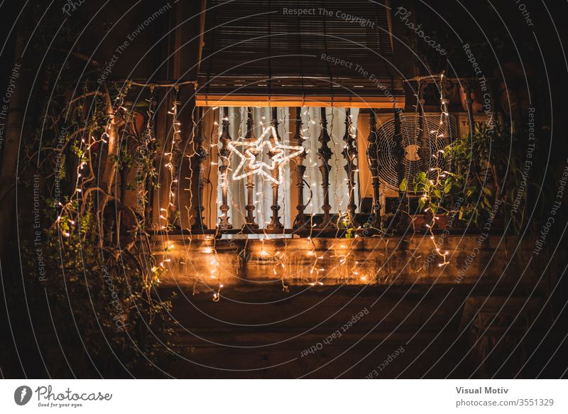 Ein heller Stern, der nachts auf einem mit Lichtgirlanden geschmückten Balkon hängt leuchten Nacht Ast Dekor Glanz Baum Haus Girlande Abend dunkel Feiertag
