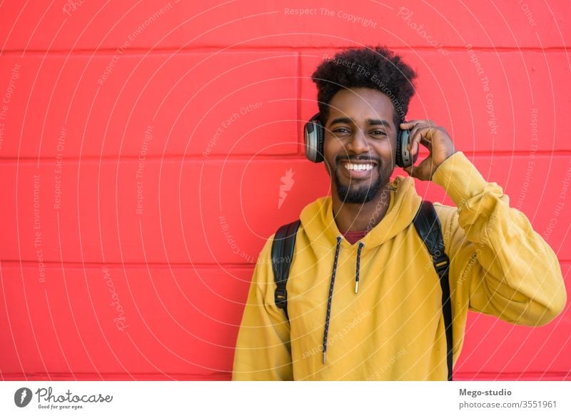 Junger Afro-Mann hört Musik mit Kopfhörern. Glück Klang Hintergrund Erwachsener modern jung freundlich Medien Ausdruck cool Im-Ohr-Gerät Ohrstöpsel tragbar