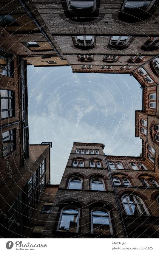 Blick nach oben in einem Innenhof; Himmel umrandet von Gebäuden; Froschperspektive Hinterhof Architektur Perspektive perspektivenwechsel Haus Menschenleer