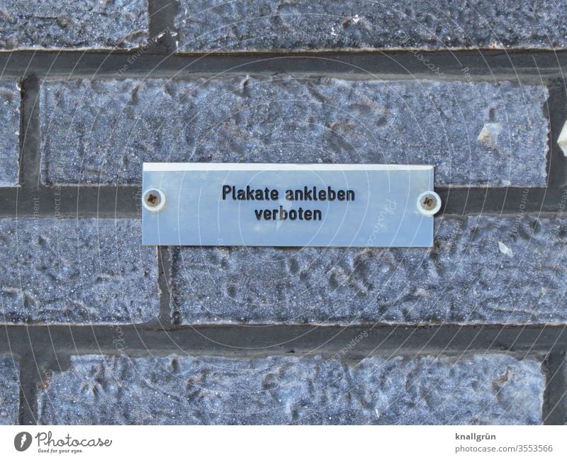 Kleines angeschraubtes Metallschild „Plakate ankleben verboten“ auf einer grauen Klinkerwand Schilder & Markierungen Verbote Kommunizieren Hinweisschild