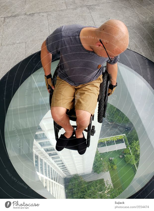 Von oben betrachtet. Rollstuhlfahrer auf einer Glasplattform rollstuhlfahrer Mobilität Mensch Selbstständigkeit Gesundheit Farbfoto Lifestyle Hoffnung Abenteuer
