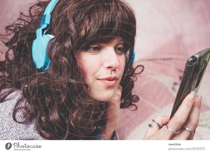 Junge brünette Frau, die in ihrem Schlafzimmer Musik hört Kopfhörer genießen Jugend hören Musik hören Freizeit Hobby zu Hause Quarantäne Technik & Technologie