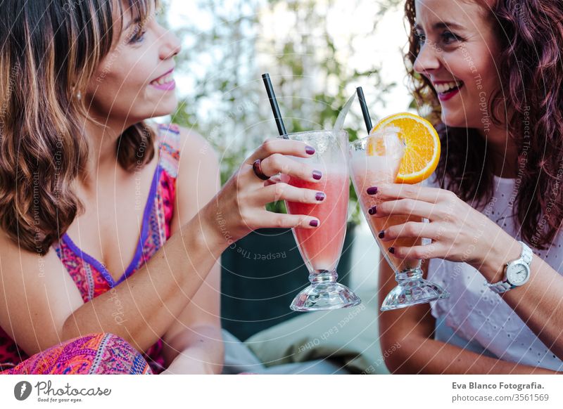 zwei Freunde genießen einen gesunden Smoothie auf einer Terrasse. Sommerzeit und Freundschaft Frauen Glück Gesundheit Saft Frucht eisbedeckt grün süß Koffein
